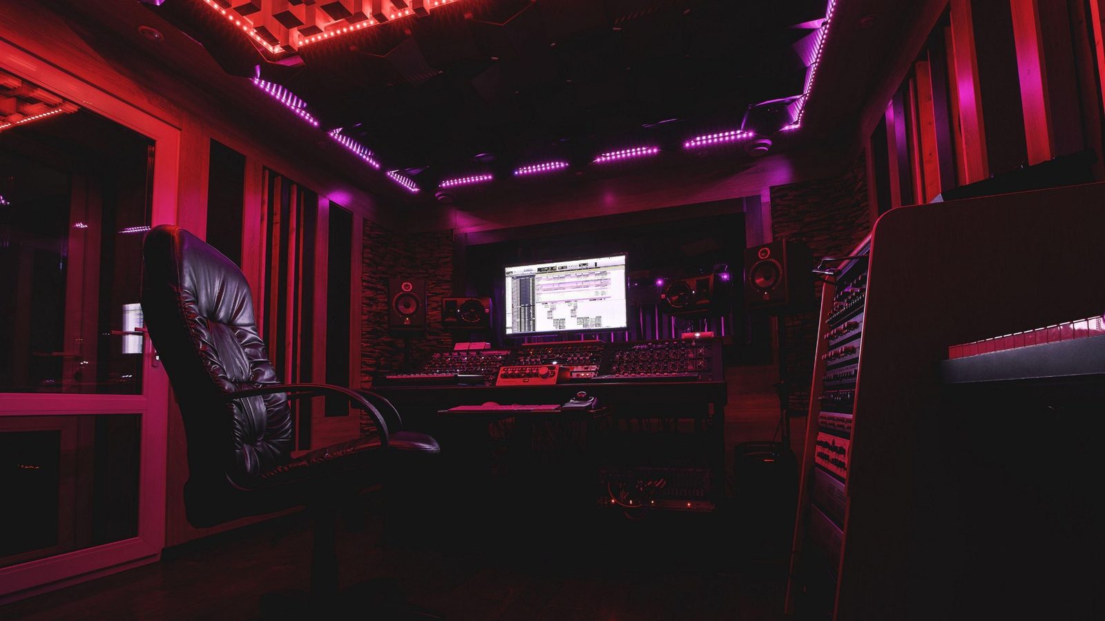 Régie de studio avec console, écran et éclairage rouge et violet